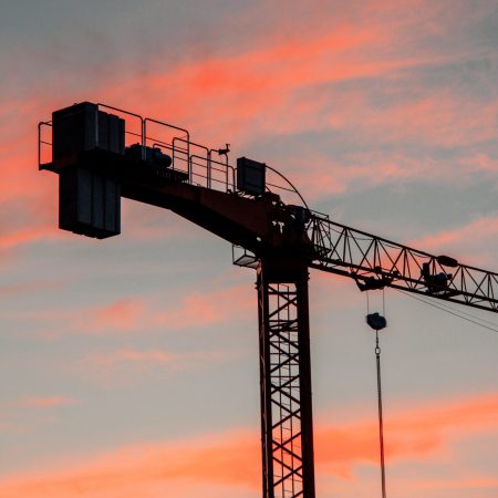 A vertical shot of an industrial construction crane during sunset